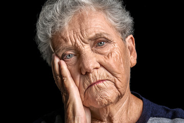 Depressed elderly woman on dark background