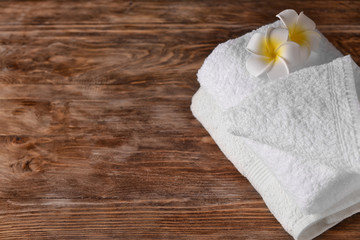 Obraz na płótnie Canvas Clean soft towel with flowers on wooden table