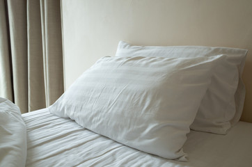 white crumpled pillows on hotel bed after use; relaxing holiday concept