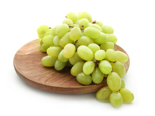 Wooden board with ripe juicy grapes on white background