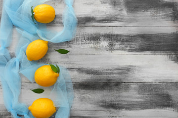 Fresh ripe lemons with color cloth on wooden background