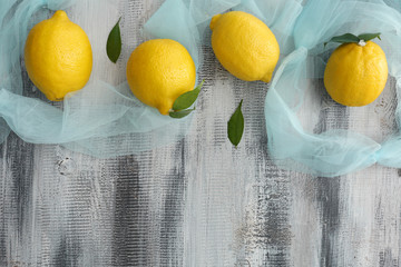 Fresh ripe lemons with color cloth on wooden background