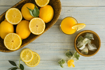 Wicker basket with ripe lemons and glass of fresh juice on wooden table