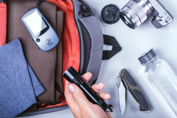 hand of man packing clothes in the backpack for travel with accessories. travel concept © Sergey