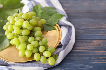 Metal tray with ripe juicy grapes on wooden table
