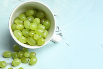 Cup with ripe juicy grapes on light table