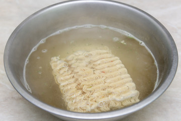 Instant noodles in a plate, covered with boiling water, junk food