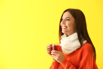 Woman with glass cup of delicious mulled wine on color background