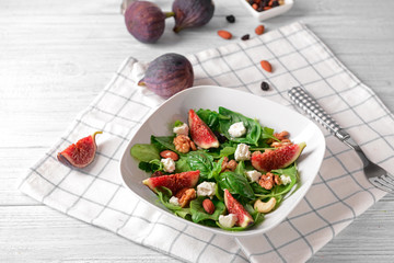 Plate with delicious fig salad on light wooden table