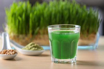 Glass of fresh wheat grass juice on table