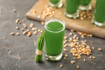 Glass of fresh wheat grass juice on table