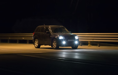 Naklejka na ściany i meble car moves in the dark along the road lit by headlights