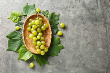 Plate with ripe sweet grapes on grey background