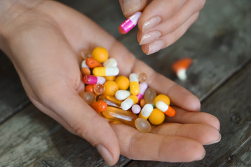 Female hands with pills on wooden background, closeup