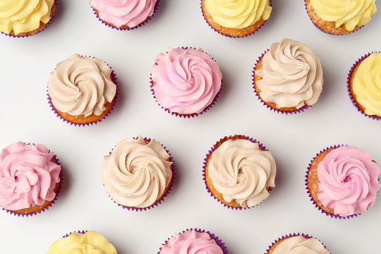 Delicious cupcakes on white background, flat lay