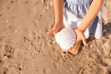 Cute little girl with sea shell on beach, closeup