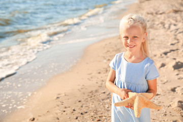 Cute little girl with starfish on sea beach