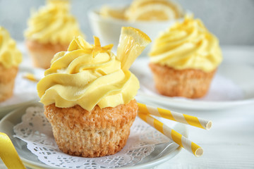 Plate with delicious lemon cupcake on table