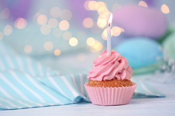 Delicious birthday cupcake with burning candle on table