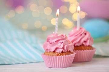 Delicious birthday cupcakes with burning candles on table