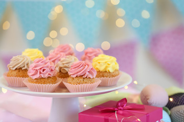 Stand with delicious cupcakes and gift box on table