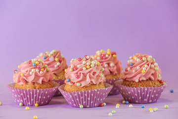 Delicious birthday cupcakes on color background