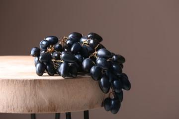 Ripe sweet grapes on table against color background