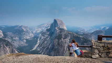 Fototapeten view of half dome at yosemite national park with young tourist taking a photo © Juan