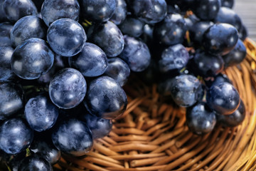 Ripe sweet grapes on wicker plate, closeup