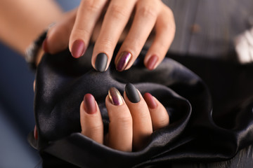 Woman with stylish beautiful manicure holding black fabric, closeup