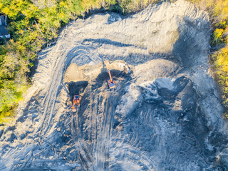 The top view of the construction site at the initial stage of construction and preparation of the ground with a two excavators loading of soil for transportation