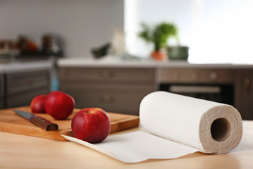 Roll of paper towels with apples and cutting board on kitchen table