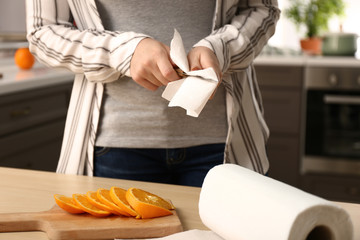 Woman wiping knife with paper towel in kitchen
