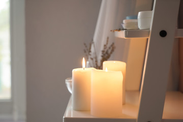 Fototapeta na wymiar Beautiful burning candles on shelf indoors