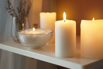 Beautiful burning candles on shelf indoors