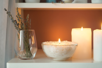 Fototapeta na wymiar Beautiful burning candles with sea salt on shelf indoors