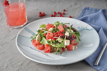 Plate with delicious watermelon salad and glass of juice on grey table