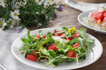 Plate with delicious watermelon salad on wooden table
