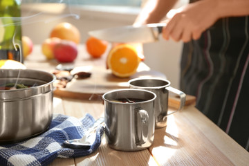 Metal cups of delicious mulled wine on wooden table