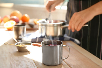 Metal cup of delicious mulled wine on wooden table