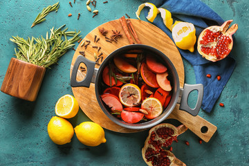 Saucepan of delicious mulled wine on wooden board