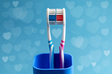 toothbrushes in plastic сup with hearts around