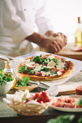Chef preparing a pizza with fresh herbs and cheese