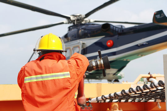Helicopter Landing Officer communicating with pilot and copilot for service on ground and support as the pilot required. The helicopter landing on the deck in oil and gas platform.