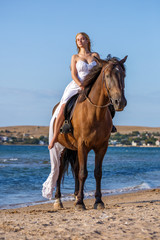 beautiful young woman in white dress by the sea with horse