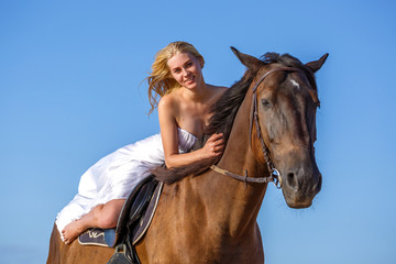 beautiful young woman in white dress by the sea with horse