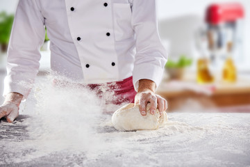 Chef rolling dough around in white flour