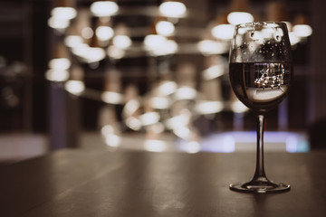 Glass with champagne lit by nightclub lights on dark background