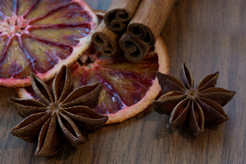 Dried Sicilian orange and dried lemon slice with cinnamon sticks and anise stars on brown wooden background, close up. Macro. Christmas mood background.