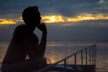 Man silhouette at sunset near the sea. he dreams and thinks about romance